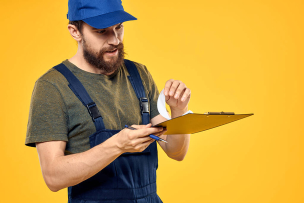 Man in working form documents transportation delivery service yellow background - Foto, Imagem