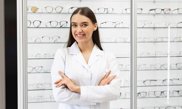 Glückliche Augenoptikerin steht im Optikgeschäft - Foto, Bild