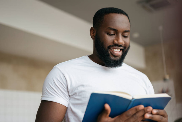 Portrait of handsome African American man reading book, exam preparation. University student studying, learning language, education concept  - Foto, afbeelding