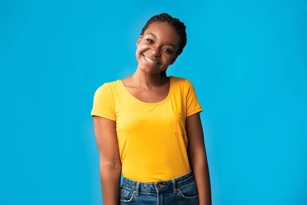 Афроамериканка с брекетами, улыбающаяся поза над синим фоном - Фото, изображение