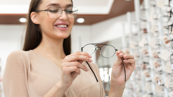 Portrait of smiling young woman choosing spectacles - Photo, Image