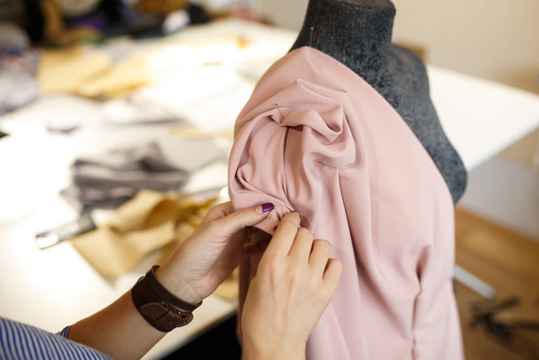 female dressmaker attach fabric to mannequin with needles. creating dress design. Tailor industry concept. - 写真・画像