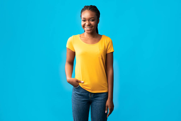 Afrikaanse Millennial vrouw met haakjes glimlachen staande over blauwe achtergrond - Foto, afbeelding