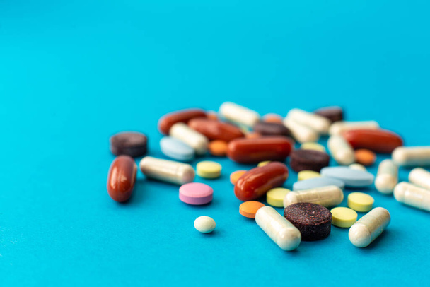 A scattered handful of colored pills on a blue background. Medical concept. - Foto, Imagem