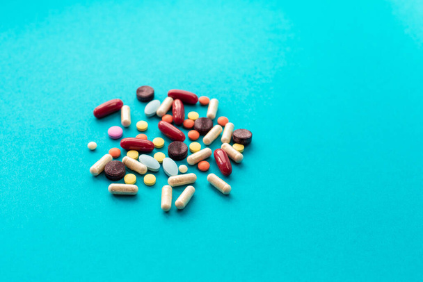 A scattered handful of colored pills on a blue background. Medical concept. - Zdjęcie, obraz