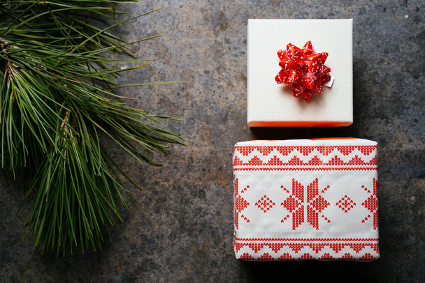 kerstcadeau doos verpakt in feestelijk papier en bureaucratie, omgeven door dennen takken op grunge blauwe achtergrond. Kerstconcept thuis - Foto, afbeelding