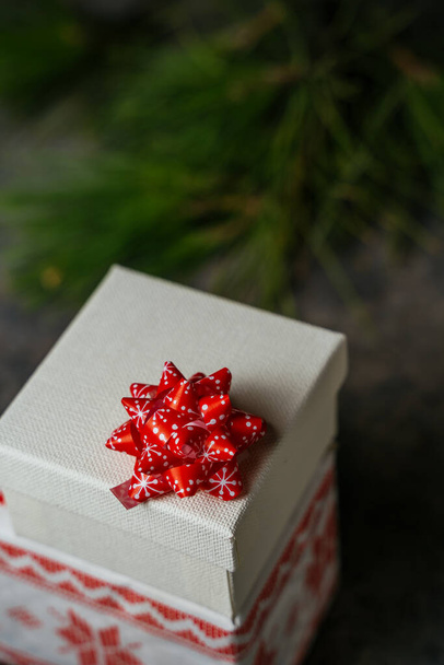 Noel hediyesi kutusu, bayram kâğıdı ve bürokrasiye sarılı. Etrafı, grunge mavisi arka planda çam dallarıyla çevrili. Evde Noel konsepti - Fotoğraf, Görsel