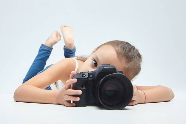 little girl with glasses, lying in the Studio with a camera. - Φωτογραφία, εικόνα