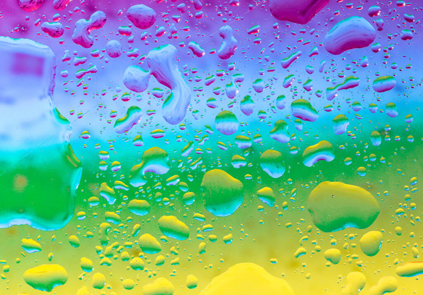 water drops background...Beautiful rainbow background lilac green color with large drops of water, top view close-up. - Foto, immagini