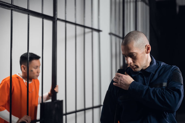 Een strenge, kale gevangenisdirecteur maakt de rondes van de cellen en stuurt informatie via de radio door naar het hoofd van de gevangenisbewaker.. - Foto, afbeelding