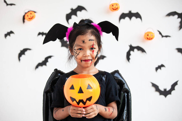 lindo asiático niño chica usando halloween trajes y maquillaje tener divertido en halloween celebración - Foto, imagen