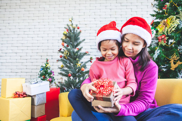 Niedliche asiatische Kind Mädchen mit ihrer Mutter hält schöne Geschenk-Box und Überraschung mit Geschenk in der Weihnachtsfeier - Foto, Bild