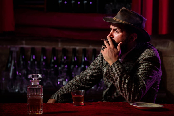 Bearded man smoking cigarette and holding glass of whiskey. - Fotografie, Obrázek