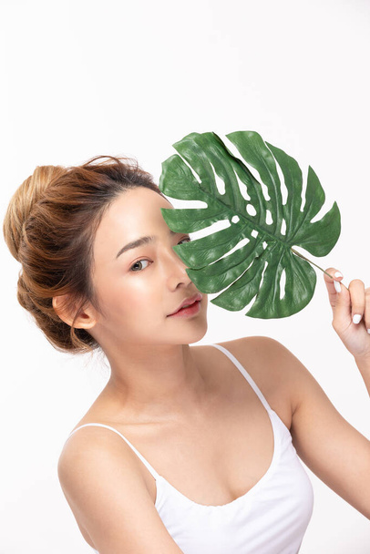 Young Beautiful Asian woman smile with clean and fresh skin with green leaf cover on face,isolated on white background,Beauty Cosmetics and spa Treatment Concept - Φωτογραφία, εικόνα