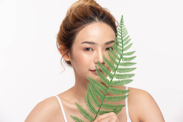 Young Beautiful Asian woman smile with clean and fresh skin with green leaf cover on face,isolated on white background,Beauty Cosmetics and spa Treatment Concept - 写真・画像