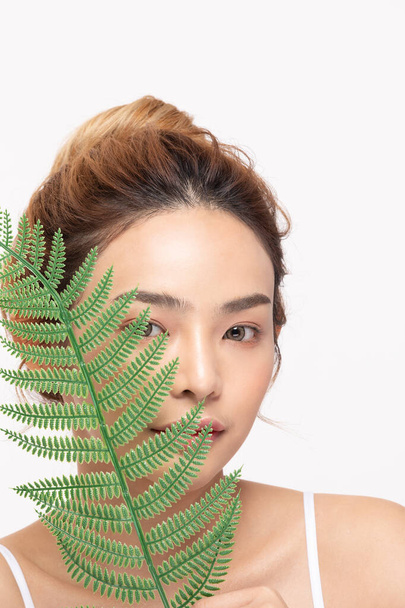 Young Beautiful Asian woman smile with clean and fresh skin with green leaf cover on face,isolated on white background,Beauty Cosmetics and spa Treatment Concept - Fotografie, Obrázek