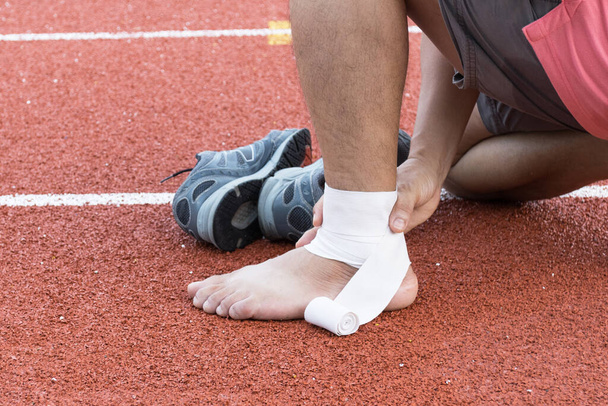 hombre aplicando vendaje de compresión sobre la lesión del tobillo Después del concepto de ejercicio Lesiones deportivas - Foto, Imagen
