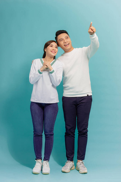 Young asian couple isolated on blue background pointing finger to the side - Foto, afbeelding