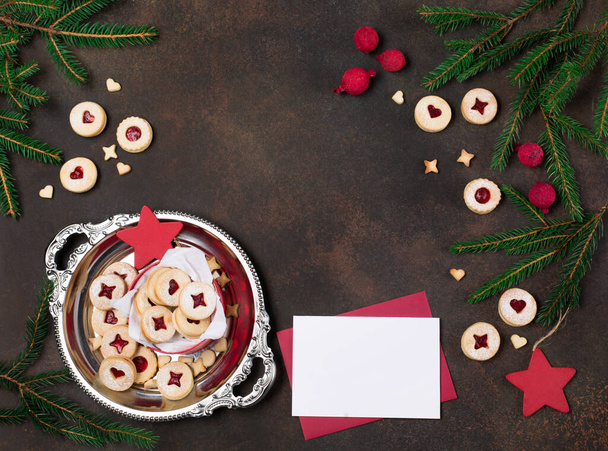 Natal de Linzer austríaco tradicional, biscoitos de Ano Novo enchidos de engarrafamento e açúcar empoeirado no fundo escuro. Presente doce caseiro em caixa festiva, envelope de artesanato, ramos de cartão e abeto. Vista superior. - Foto, Imagem