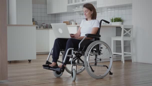 Niepełnosprawna kobieta na wózku inwalidzkim przy użyciu laptopa - Materiał filmowy, wideo