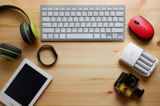 Weiße Tastatur mit drahtloser Maus und Bluetooth-Funkkopfhörern und anderen elektronischen Geräten für den täglichen Gebrauch auf hölzernem Hintergrund. Draufsicht. - Foto, Bild