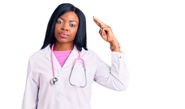 Młoda Afroamerykanka nosząca stetoskop lekarski, strzelająca i zabijająca się, celująca ręką i palcami w głowę, jak broń, gest samobójczy..  - Zdjęcie, obraz