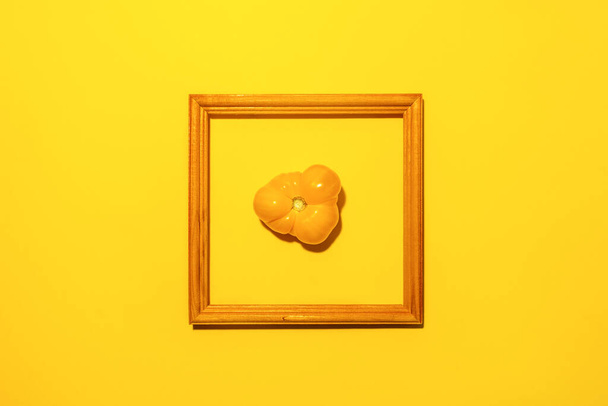 One yellow farm tomatoes in center of square wooden frame on bright yellow background with copy space. Food as art. - Φωτογραφία, εικόνα