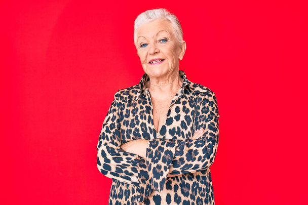 Senior beautiful woman with blue eyes and grey hair wearing casual and modern leopard animal print shirt happy face smiling with crossed arms looking at the camera. positive person.  - Foto, Bild