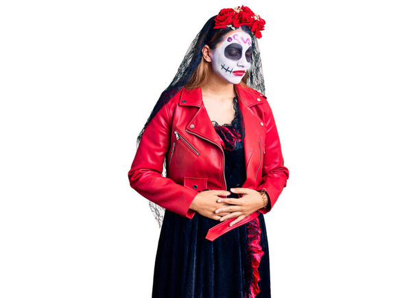 Женщина носит день мертвого костюма на заднем плане с рукой на животе, потому что несварение желудка, болезненная болезнь чувствует себя нездоровым. Концепция.  - Фото, изображение
