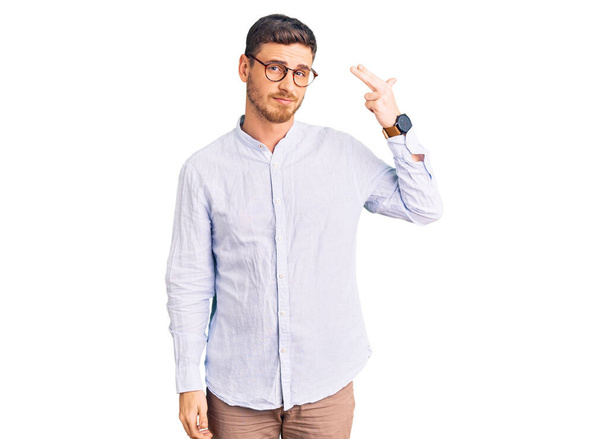 Handsome young man with bear wearing elegant business shirt and glasses shooting and killing oneself pointing hand and fingers to head like gun, suicide gesture.  - Photo, Image