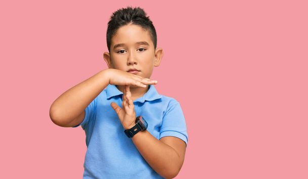 Kleiner hispanischer Junge in lässiger Kleidung macht eine Auszeit mit Händen, frustriertem und ernstem Gesicht  - Foto, Bild