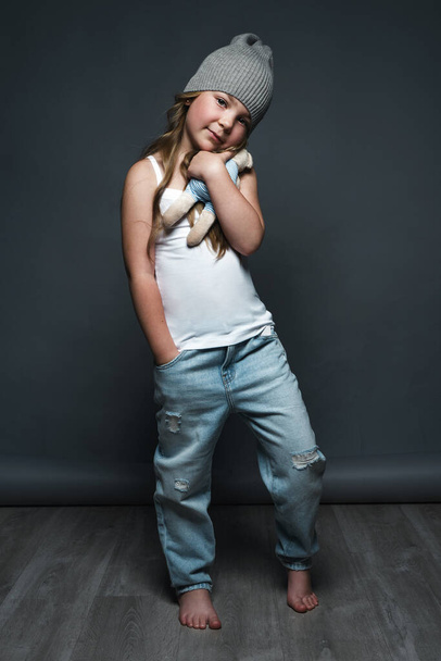 Little girl model professionally posing in the studio in jeans and a white T-shirt. Model tests - 写真・画像