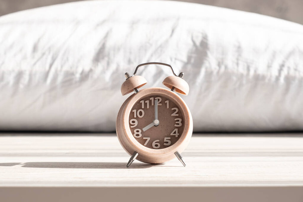 Будильник стоит на подушке под утренним солнечным светом, утреннее время пробуждения, время сна, здоровый сон - Фото, изображение
