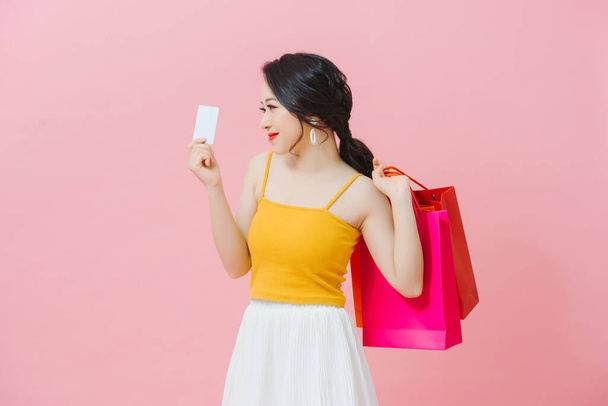 Portret van een mooie charmante vrouw met veel kleurrijke tassen in handen gebaren credit plastic bankkaart  - Foto, afbeelding