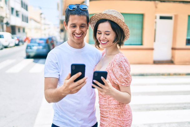Krásný pár usměvavý šťastný pomocí smartphone na ulici města - Fotografie, Obrázek