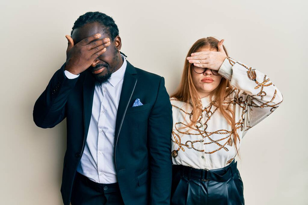 Mladý mezirasový pár nosí obchodní a elegantní oblečení zakrývající oči rukou, vypadá vážně a smutně. nevidomý, skrývající a odmítavý koncept  - Fotografie, Obrázek