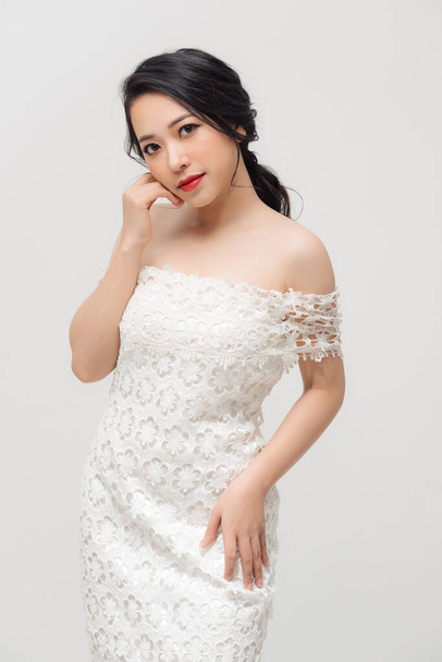 Hermosa mujer joven asiática en vestido blanco posando sobre el fondo blanco. Belleza, moda. Cuidado del cabello. Cosméticos. - Foto, Imagen