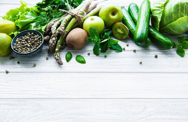 Sağlıklı vejetaryen gıda konsepti, detoks diyeti için taze yeşil gıda seçimi, elma, salatalık, kuşkonmaz, avokado, limon, beyaz ahşap arka planda salata üstü görünümü. - Fotoğraf, Görsel