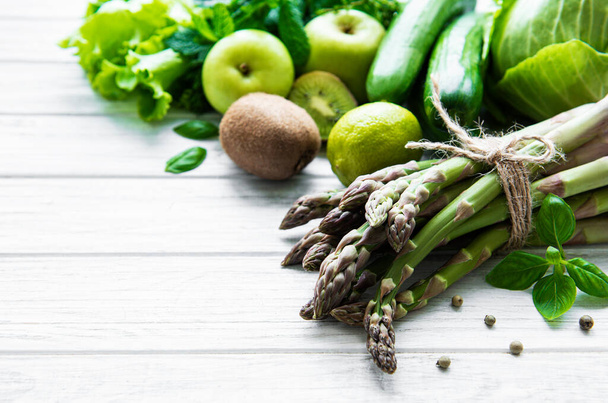 Terveellinen kasvisruoka konsepti tausta, tuoretta vihreää ruokaa valinta detox ruokavalio, omena, kurkku, parsa, avokado, lime, salaatti ylhäältä näkymä valkoinen puinen tausta - Valokuva, kuva