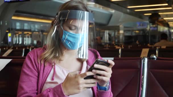 Mujer con máscara médica y protector facial en el aeropuerto - Metraje, vídeo
