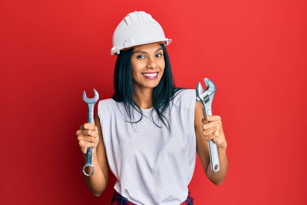 Young african american woman wearing hardhat holding wrench smiling with a happy and cool smile on face. showing teeth.  - Foto, Bild