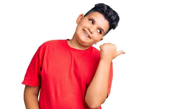 Little boy kid wearing casual clothes smiling with happy face looking and pointing to the side with thumb up.  - 写真・画像
