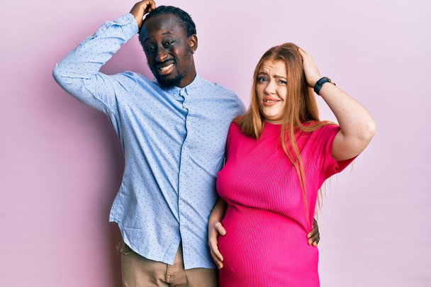 Jovem casal interracial esperando um bebê, tocando barriga grávida confundir e se perguntando sobre a pergunta. incerto com a dúvida, pensando com a mão na cabeça. conceito pensativo.  - Foto, Imagem