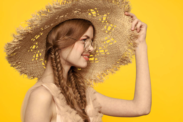 Portrait d'une jolie femme avec des nattes et un chapeau sur la tête sur un fond jaune vue recadrée - Photo, image
