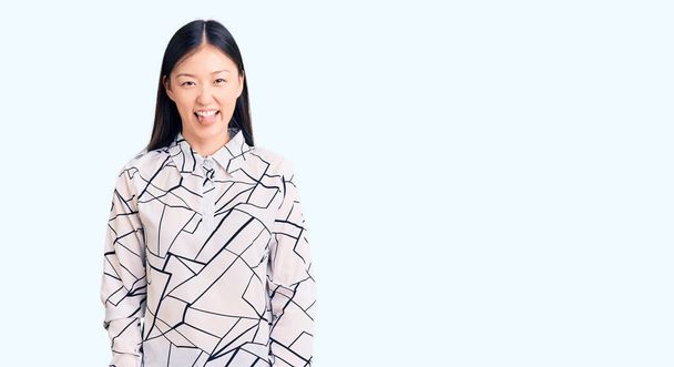 Mladý krásný číňan žena na sobě ležérní tričko vyčnívat jazyk šťastný s legrační výraz. koncepce emocí.  - Fotografie, Obrázek