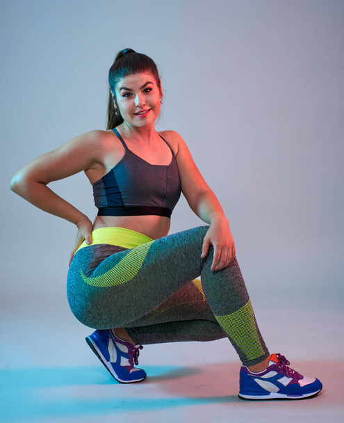 Plus size confident beautiful young woman doing fitness exercises, blue-red toning, studio shot - Foto, afbeelding
