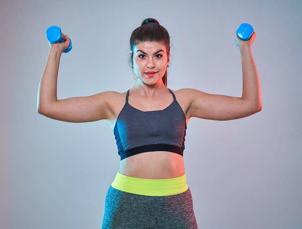 Plus size confident beautiful young woman doing fitness exercises, blue-red toning, studio shot - Fotoğraf, Görsel