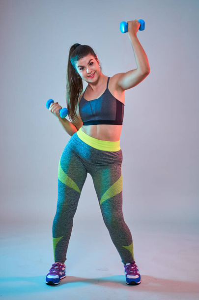 Plus size confident beautiful young woman doing fitness exercises, blue-red toning, studio shot - Foto, afbeelding