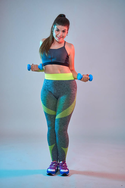 Plus size confident beautiful young woman doing fitness exercises, blue-red toning, studio shot - Photo, image