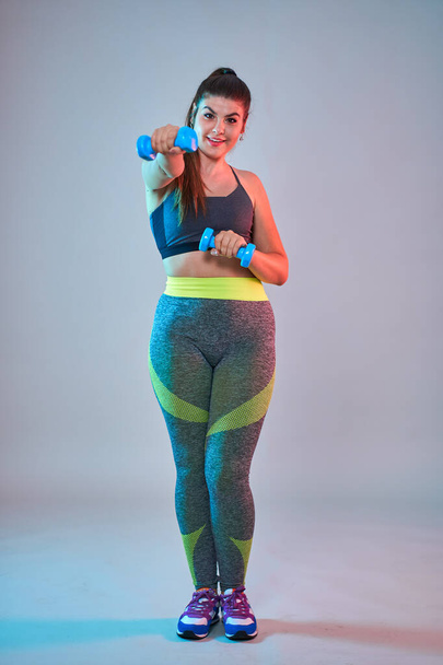 Plus size confident beautiful young woman doing fitness exercises, blue-red toning, studio shot - Valokuva, kuva